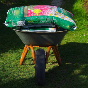 Wheelbarrow filled with gardening supplies on a grassy path